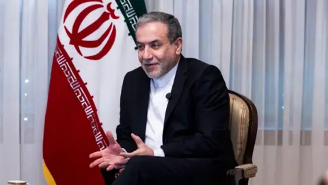 Seyed Abbas Araghchi sitting in front of a flag. 