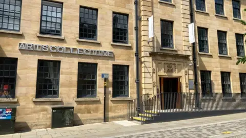 James Grant/BBC A light brick building with lots of bay windows. "Arts Collective" is written on the side of the building in capital letters. 