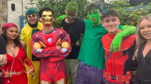 BBC/Grace Wood A group of young men and women wearing fancy dress costumes, including superhero outfits, masks and painted faces