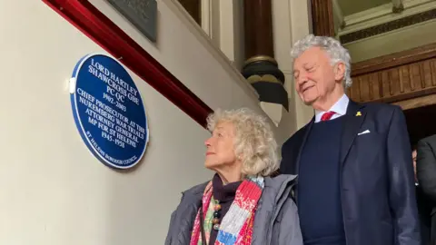 Sir Hartley Shawcross' son and daughter gaze up at the blue plaque to their father