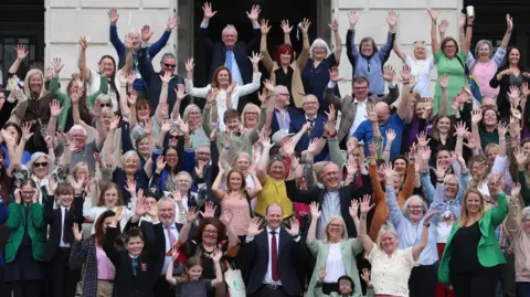 Communities minister Gordon Lyons (centre front) with campaigners from the deaf community at a rally outside the Parliament Buildings at Stormont.