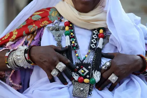 BILLEL BENSALEM / NURPHOTO / GETTY IMAGES A woman wear chunky silver rings, bracelets and an elaborate necklace.