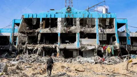 Getty Images A man walks past the destroyed UN Palestinian refugee agency in Jabaliya