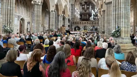 A large congregation face the altar in a cathedral.