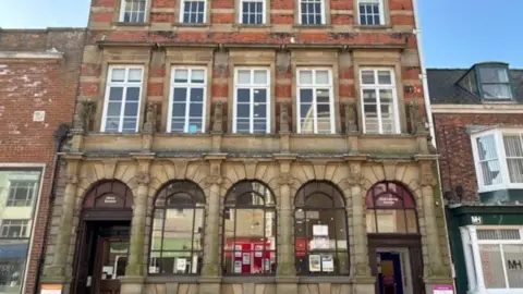 East Riding of Yorkshire Council An exterior view of Bridlington Central Library. The building has stone pillars and arched windows on the ground floor, with Georgian-style bar windows on the upper floors.