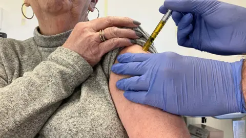 BBC Close up of a woman being given a trial vaccination dose