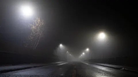 Getty Images Looking up at a road and street lights on an atmospheric foggy winter's night on a UK road 