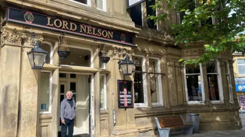 Customer smoking in the doorway of the Lord Nelson pub in Nelson