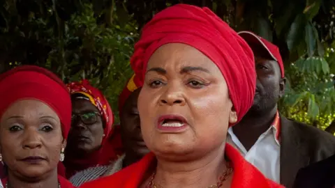 AFP Archive headshot of Patricia Kaliati form June 2024 speaking while wearing a red head wrap.