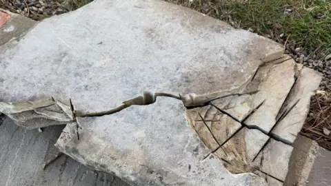 Anna Lamb A rectangular stone which has been damaged with cuts in it and pieces removed. 