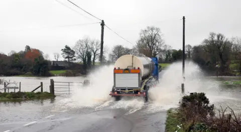 A truck driving through a flooded road.