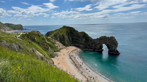 TUESDAY - A sunny day overlooking the natural arch at Durdle Door with people lying on the beach