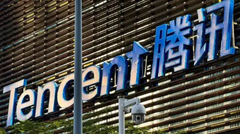 Getty Images The Tencent logo displayed on the exterior of a building at the company’s headquarters in Shenzhen, China. There is a surveillance camera in the foreground.