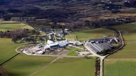 An aerial view of Clynelish Distillery in Brora. The distillery is made up of a number of large buildings and is is set in a rural landscape of fields.