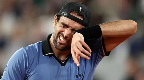 Matteo Berrettini wipes his face with a sweatband on his wrist