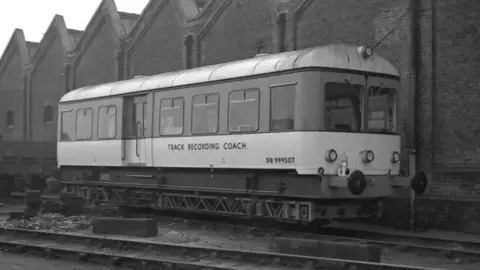 Stuart Mackay Collection An archive image of a track recording coach parked on the rail tracks. There is a watermark for Stuart Mackay Collection and a railcar's website.
