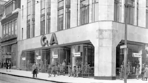 streets-UK A black and white image of a large shop in the 1930s or 40s. Various people are walking by and a large C & A sign is above the shop windows 