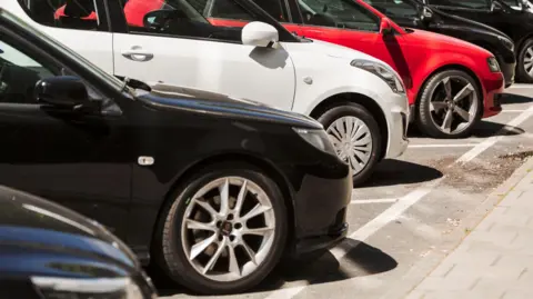 Getty Images Several cars parking diagonally, side by side in parking bays.