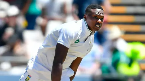Kagiso Rabada, wearing Test whites, in the follow-through of bowling for South Africa
