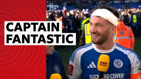 Paul Dawson smiles in an interview with a bandage around his forehead