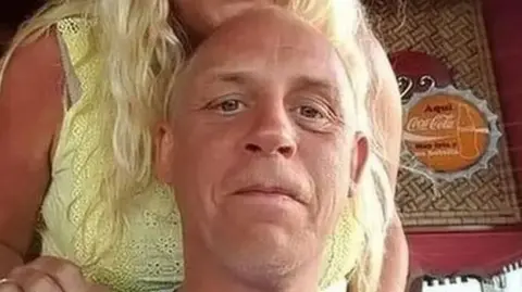 Lancashire Police handout Tony Johnson is smiling as he looks into the camera, with a woman standing behind him, whose face cannot be seen.