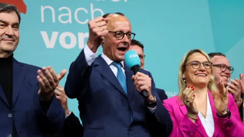 German conservative candidate for chancellor and Christian Democratic Union (CDU) party leader Friedrich Merz pumps his first while holding a microphone