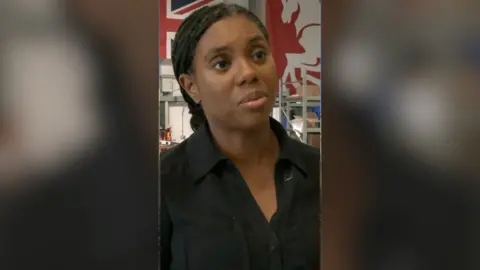 Kemi Badenoch in black.