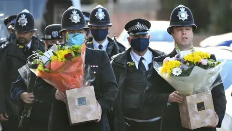 PA Media Police officers holding flowers