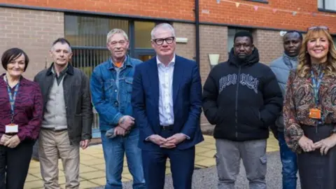 West Midlands Combined Authority A group standing in a line outside a modern building, posing facing the camera. Five men are pictured, with two women either side.