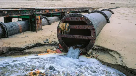 Getty Images Wastewater being discharged into the sea on a UK beach