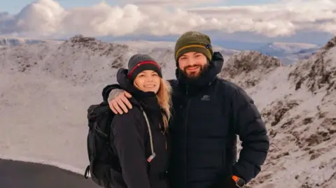 Supplied Damon Alexander-Cole, is pictured here with his partner Kirsty Doyle, on a mountain rain on a sunny day