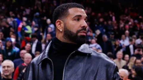 Getty Images Drake in a leather jacket while courtside at the Golden State Warriors v Toronto Raptors NBA game in January 2025