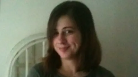 A picture of Rachael Vaughan, who is smiling at the camera. She has long brown hair and is wearing a green shirt.