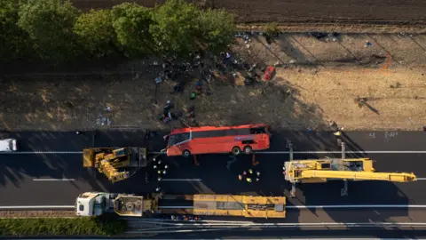 EPA Aerial shot of the bus on the motorway on its side, with cranes beside it.