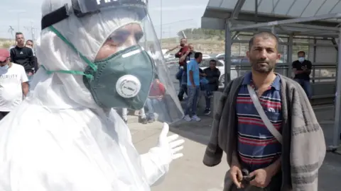 Zahid Soleiman is told by a medical worker to self-isolate at the Tarqumiya checkpoint, near the West Bank city of Hebron