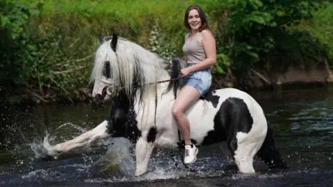 PA Media Woman on horse in river at Appleby Horse Fair 2022