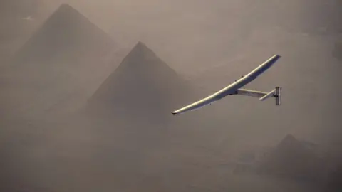Image of a small aircraft flying over pyramids.