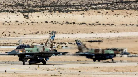Two Israeli fighter jets are taxiing at an air base in southern Israel.
