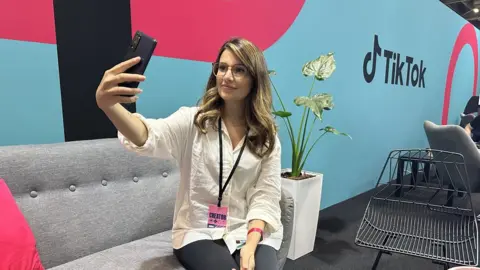 BBC Sport A woman holds a phone while sitting on a sofa