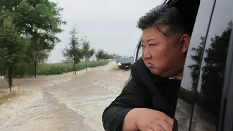 North Korean leader Kim Jong Un walks through a flooded area.