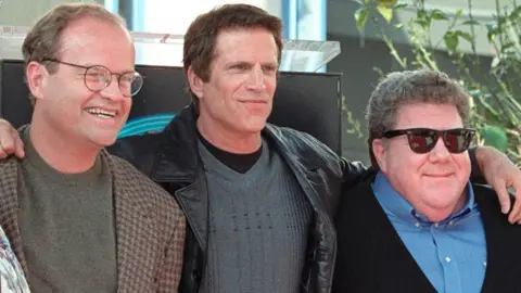 George Wendt pictured with co-stars Kelsey Grammer and Ted Danson, with arms around each other, in 1999