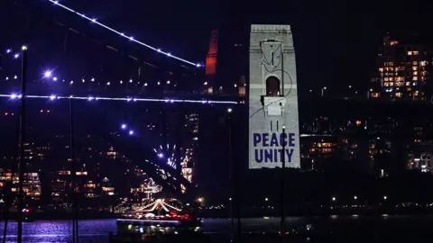 AFP via Getty Images A message read "peace, unity" Projection onto the pylons of the Sydney Harbor Bridge