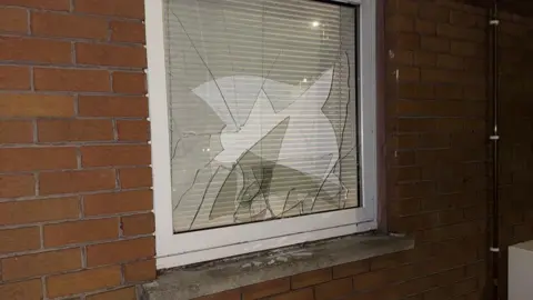 Handout A small window with smashed glass on a bricked house 