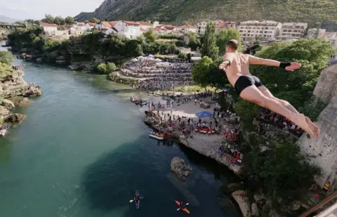 DADO RUVIC/Reuters A man diving into water from a height into the Neretva river in Mostar