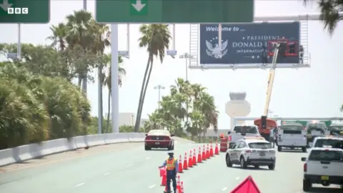 Workers installing a 'Welcome to President Donald J. Trump International Airport' sign