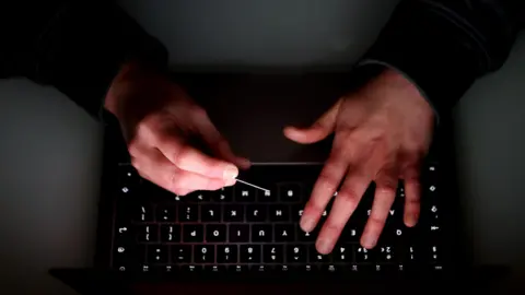 A pair of hands on a laptop keyboard.