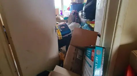 Image shows the door to a room in Ruth's flat. It cannot be opened because of how much rubbish is blocking it on both sides. 