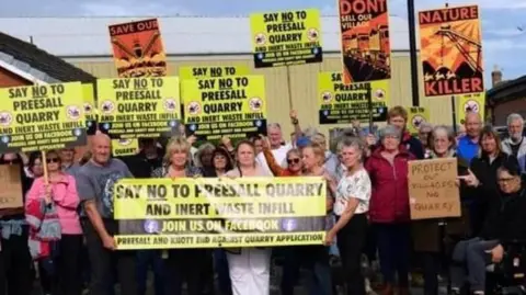 Protesters holding up placards objecting to the building of the quarry