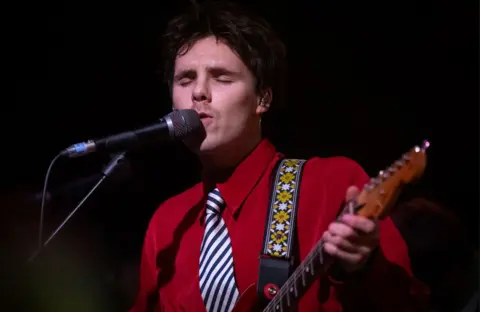 Cruz singing and playing the guitar 