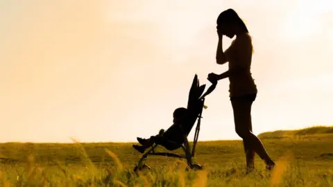 Getty Images Mother with child in pushchair in field